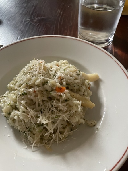 plate of asparagus risotto with parmesan and a glass of water on the side