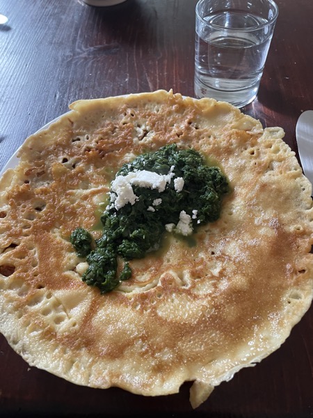 a pancake with spinach and feta cheese with a glass of water on the side