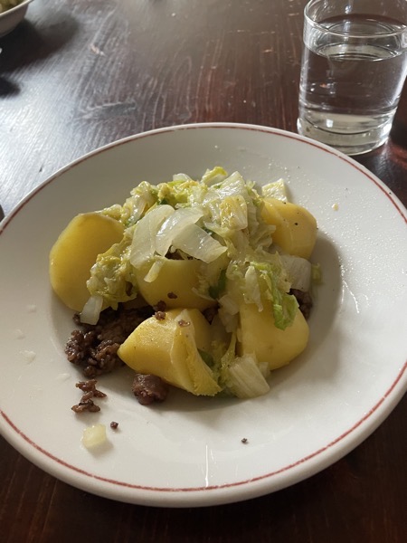 potatoes, Chinese cabbage and ground beef on a plate with a glass of water on the side