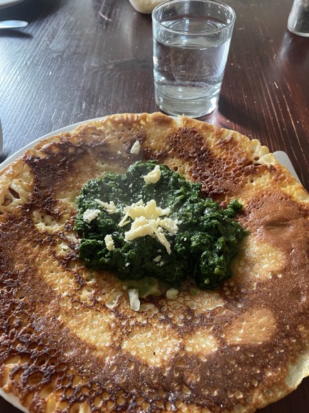 pancake with spinach and grated Cheddar with a glass of water on the side