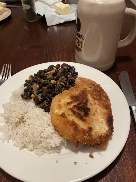 a plate of rice, black beans and chicken with a beer stein
