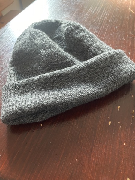 a gray Musselburgh hat on a dark brown table