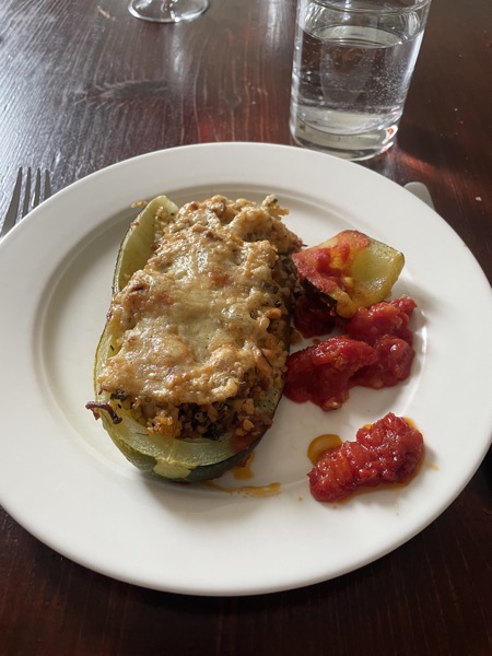 half a stuffed zucchini with tomato sauce and a glass of water