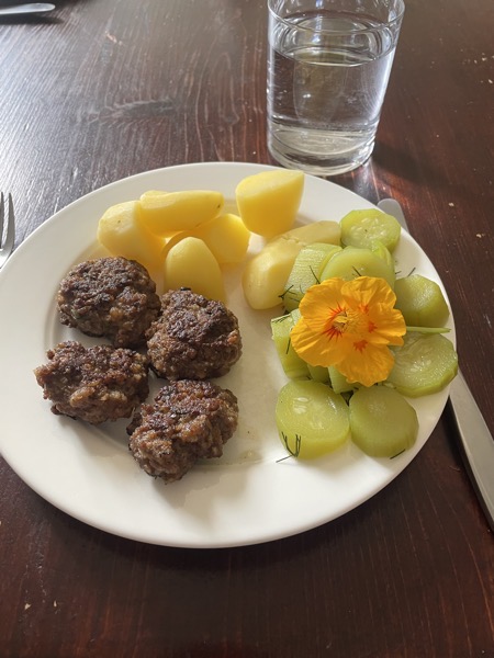 burgers, potatoes, cucumber and a glass of water