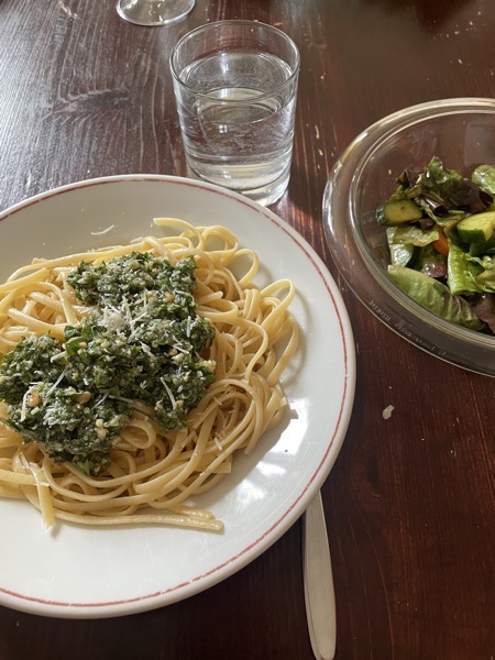 a plate of linguine with homemade pesto, some mixed salad and a glass of water