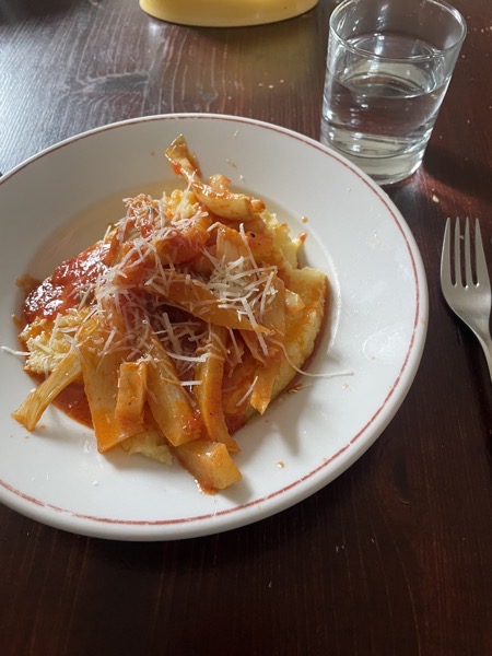 polenta with fennel in tomato sauce and parmesan with a glass of water