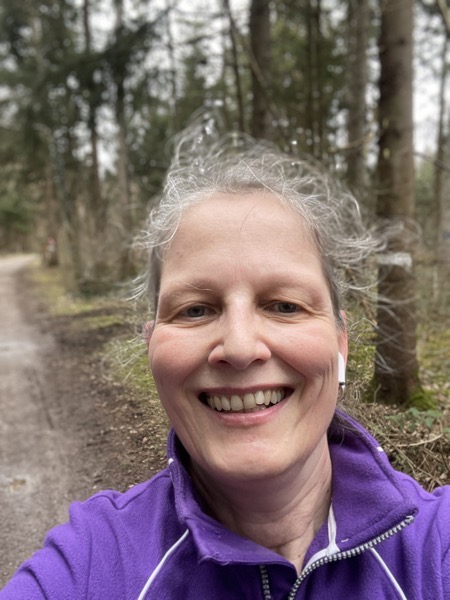 picture of Susanne in a purple fleece jacket in front of blurry pines