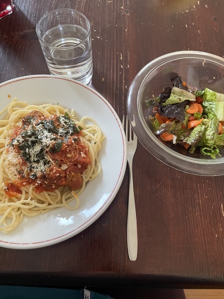 a plate of spaghetti and meatballs, a mixed salad and a glass of water