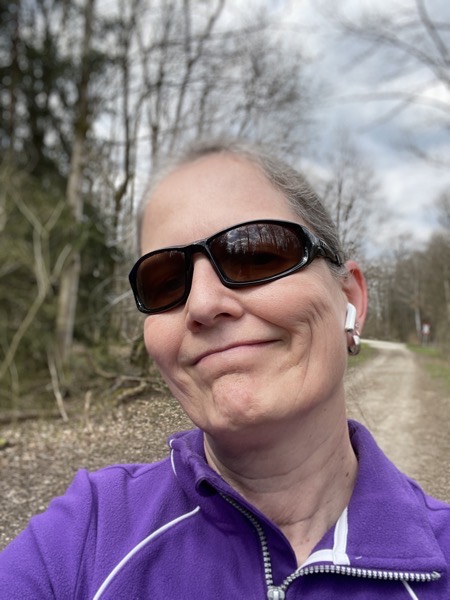 Susanne in the woods again, same purple fleece, same ugly sunglasses, same scraggly trees