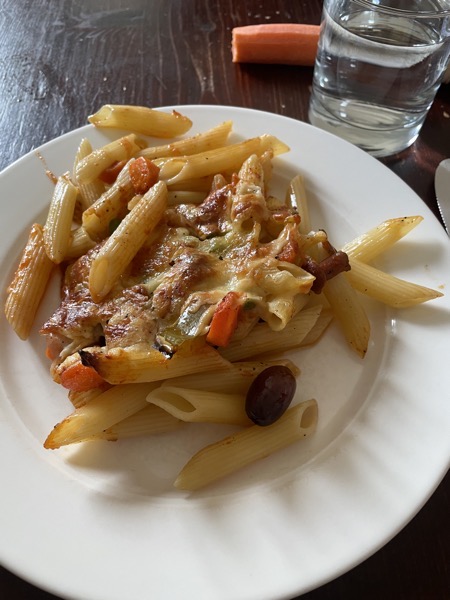 noodle casserole with veggies, a raw carrot and a glass of water