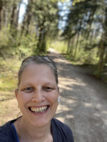 a grinning Susanne on a wood path