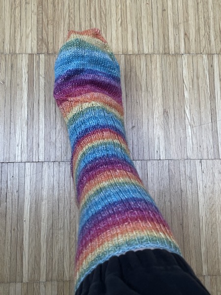 Susanne's right foor in a rainbow striped handknit sock